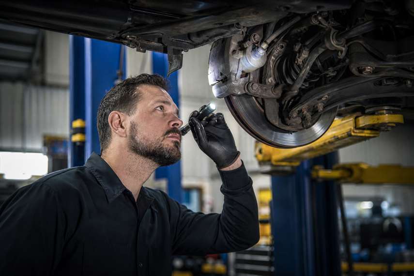 Mecânico realizando inspeção em veículo dentro de oficina